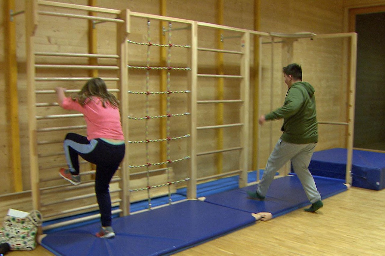 Overweight children do gymnastics on wall bars