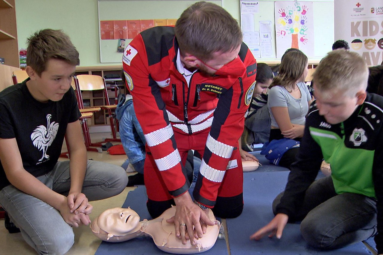Emergency doctor explains a heart massage during lifesaver course in school