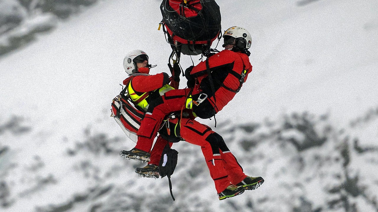 Two mountain rescuers hang on the helicopter rope