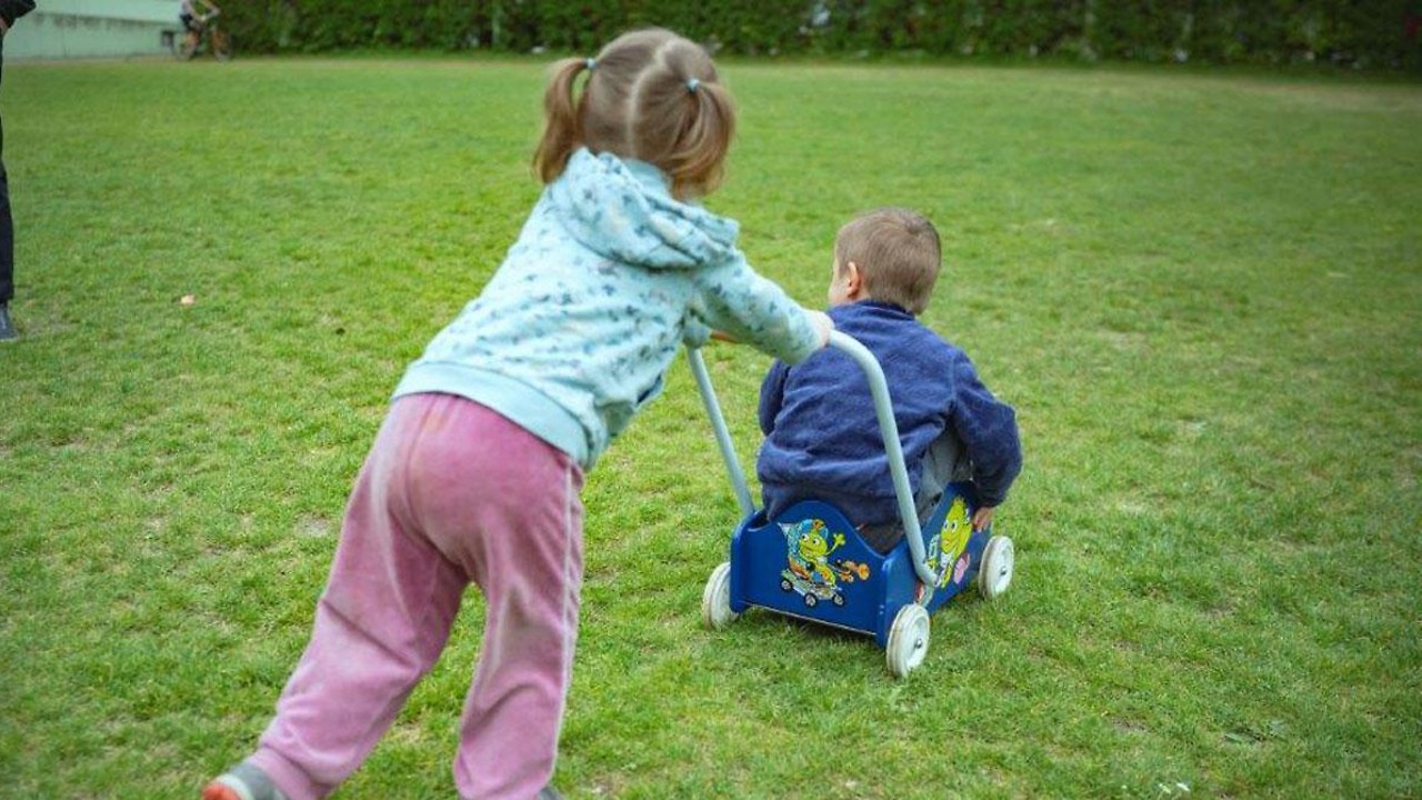 Girl pushes a boy on the meadow